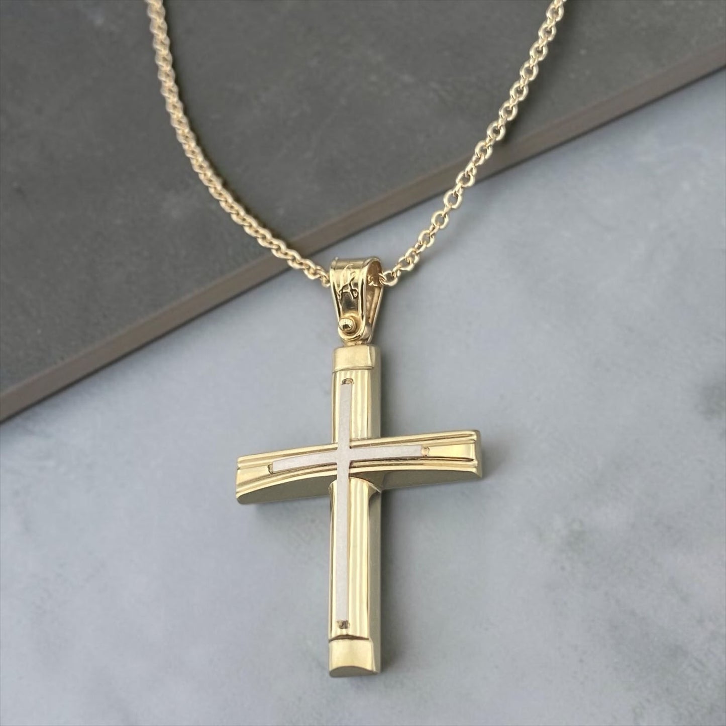 A detailed view of a 14K yellow and white gold men's cross pendant featuring a polished inlay cross design