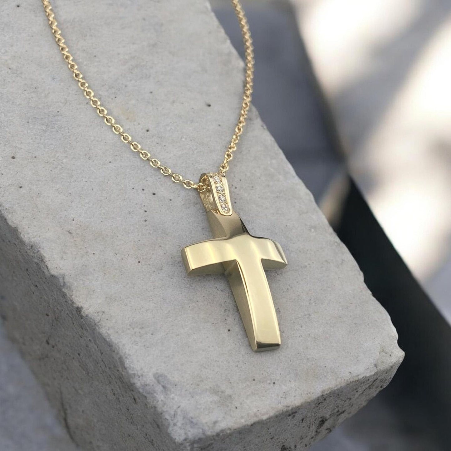 14k yellow gold cross pendant for women, featuring a smooth polished surface and sparkling zirconia stones set on the bail.