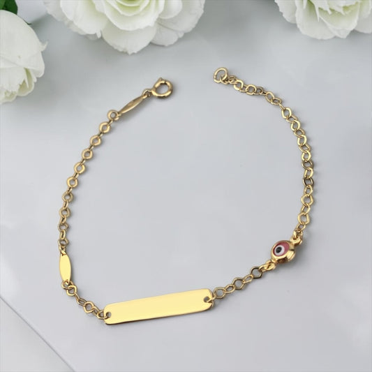 Gold bracelet with a bar clasp and eye charm on a marble surface