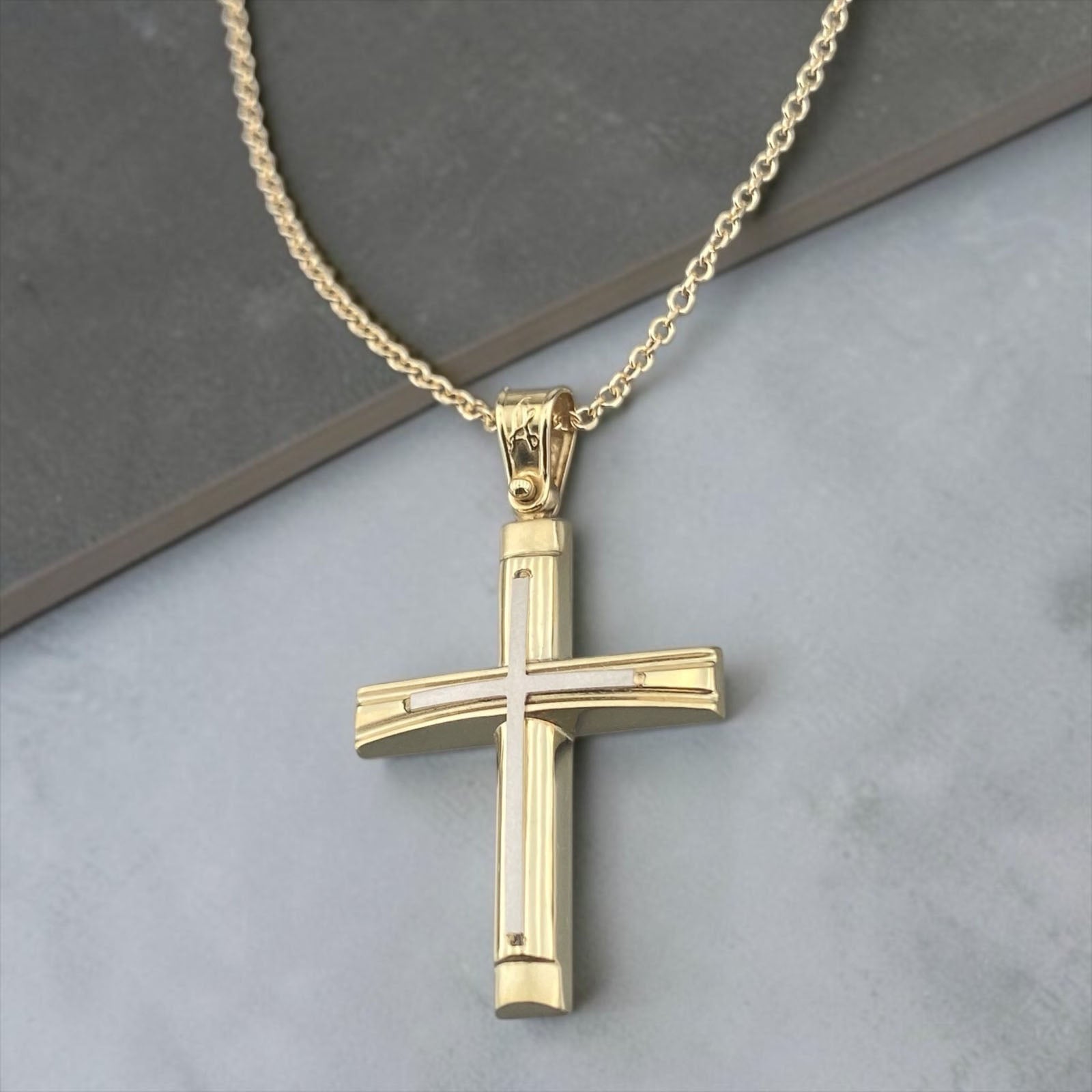 A detailed view of a 14K yellow and white gold men's cross pendant featuring a polished inlay cross design