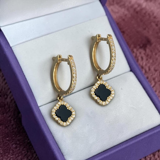 Elegant 14k yellow gold hoop earrings featuring black clover charms with sparkling crystal accents.