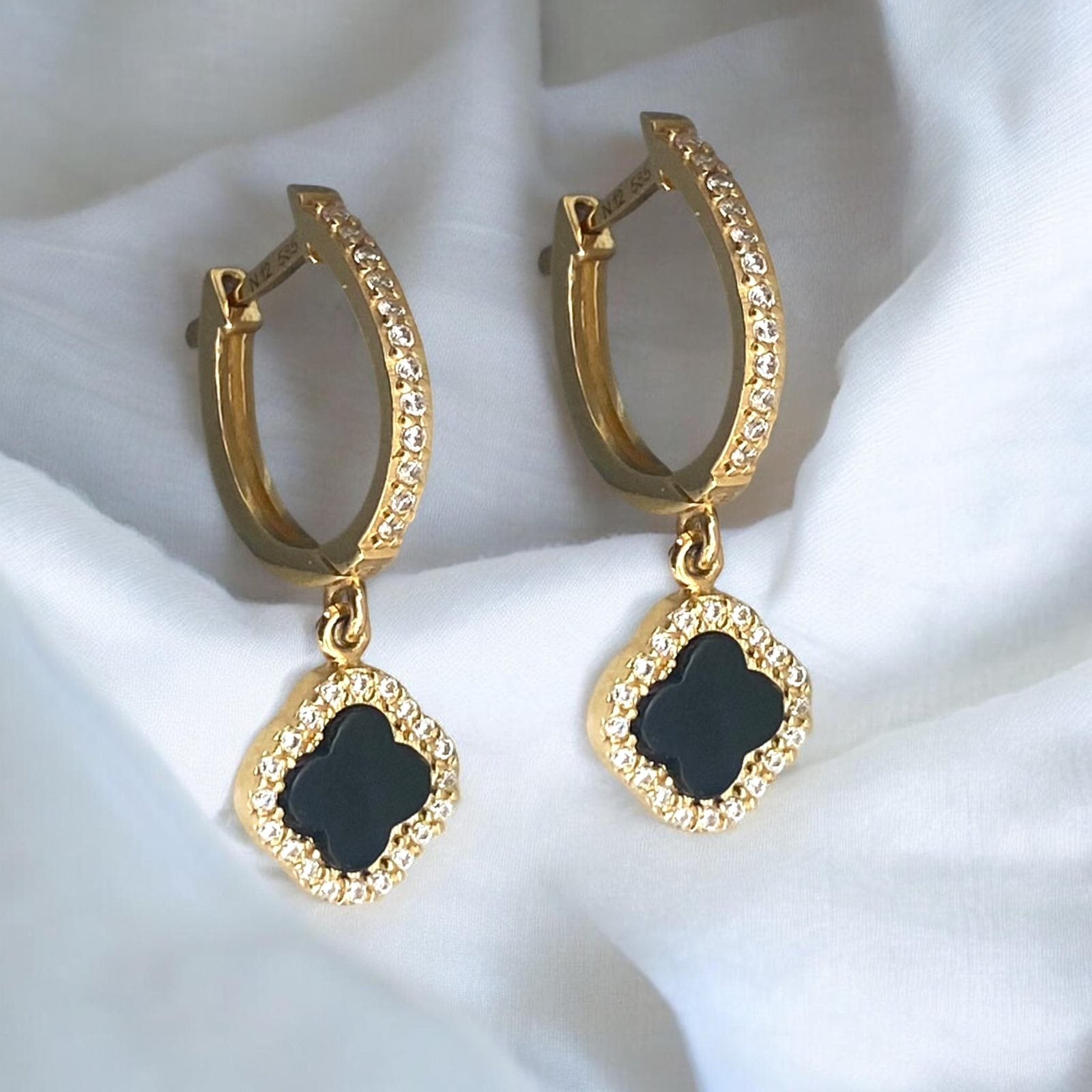 Elegant 14k yellow gold hoop earrings featuring black clover charms with sparkling crystal accents.