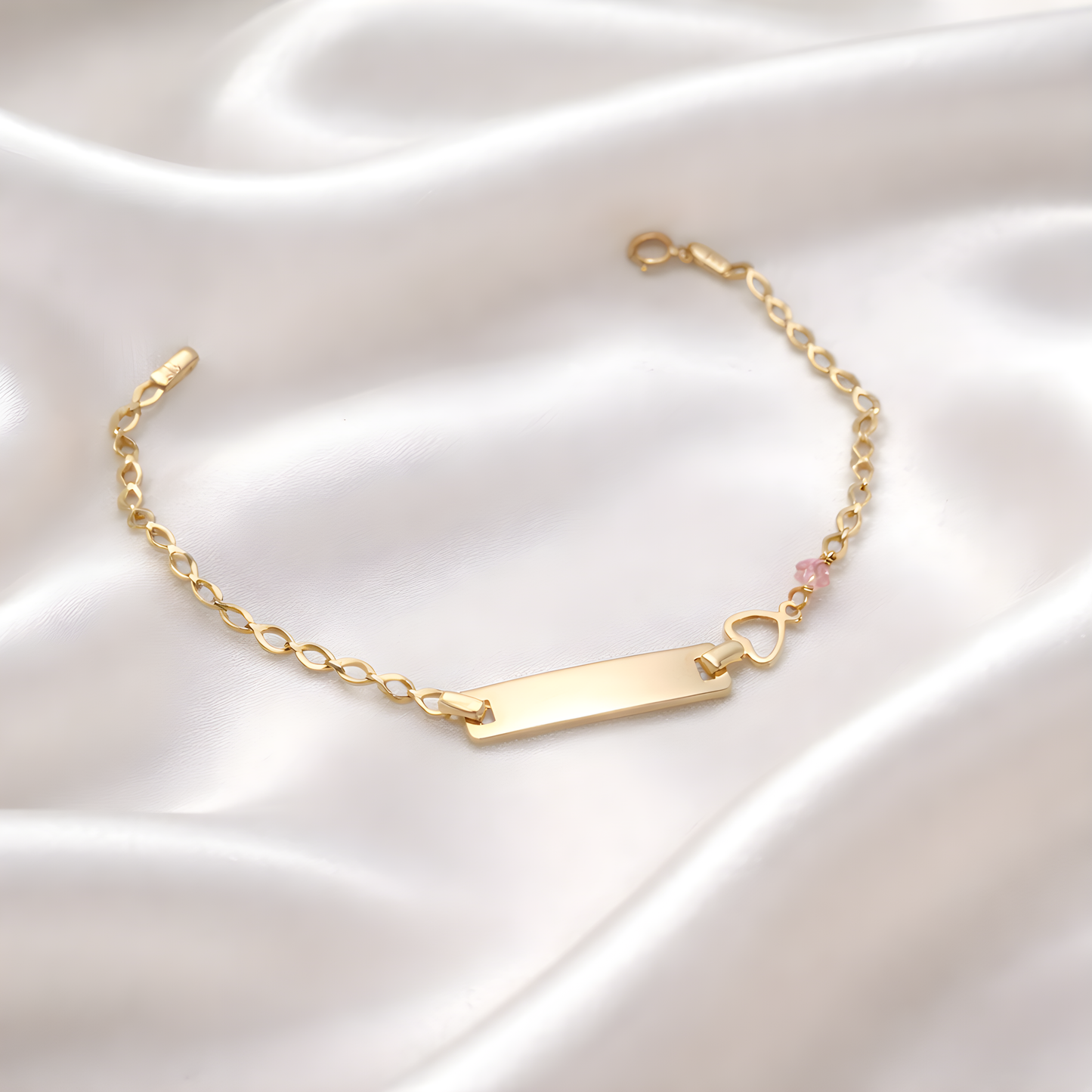 Gold bracelet with a heart charm on a satin surface