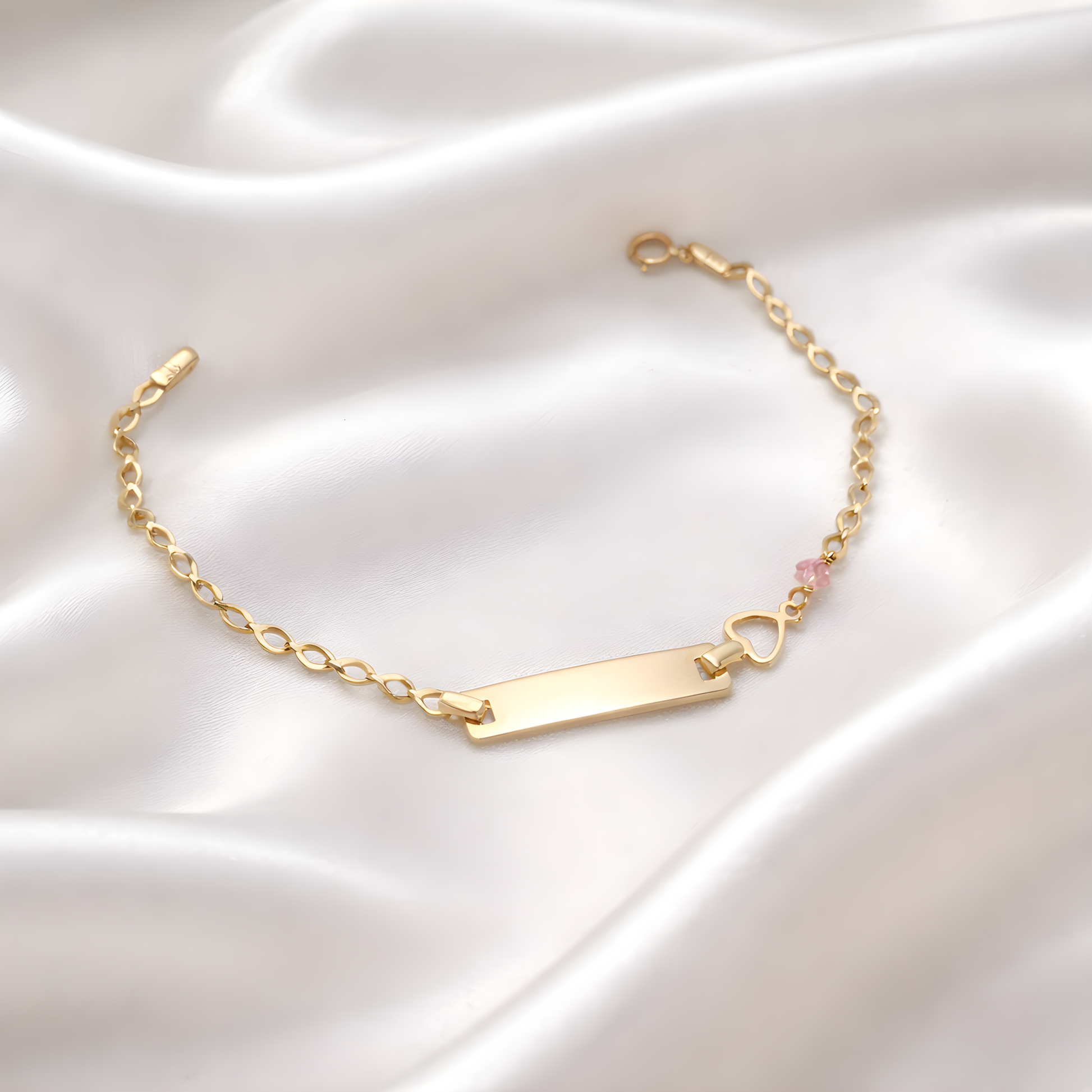 Gold bracelet with a heart charm on a satin surface