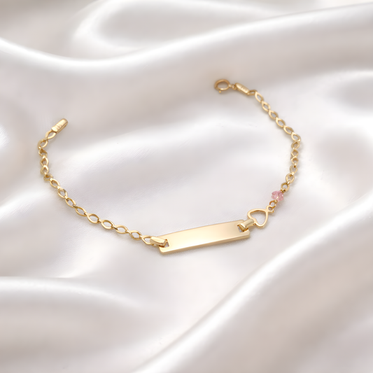 Gold bracelet with a heart charm on a satin surface