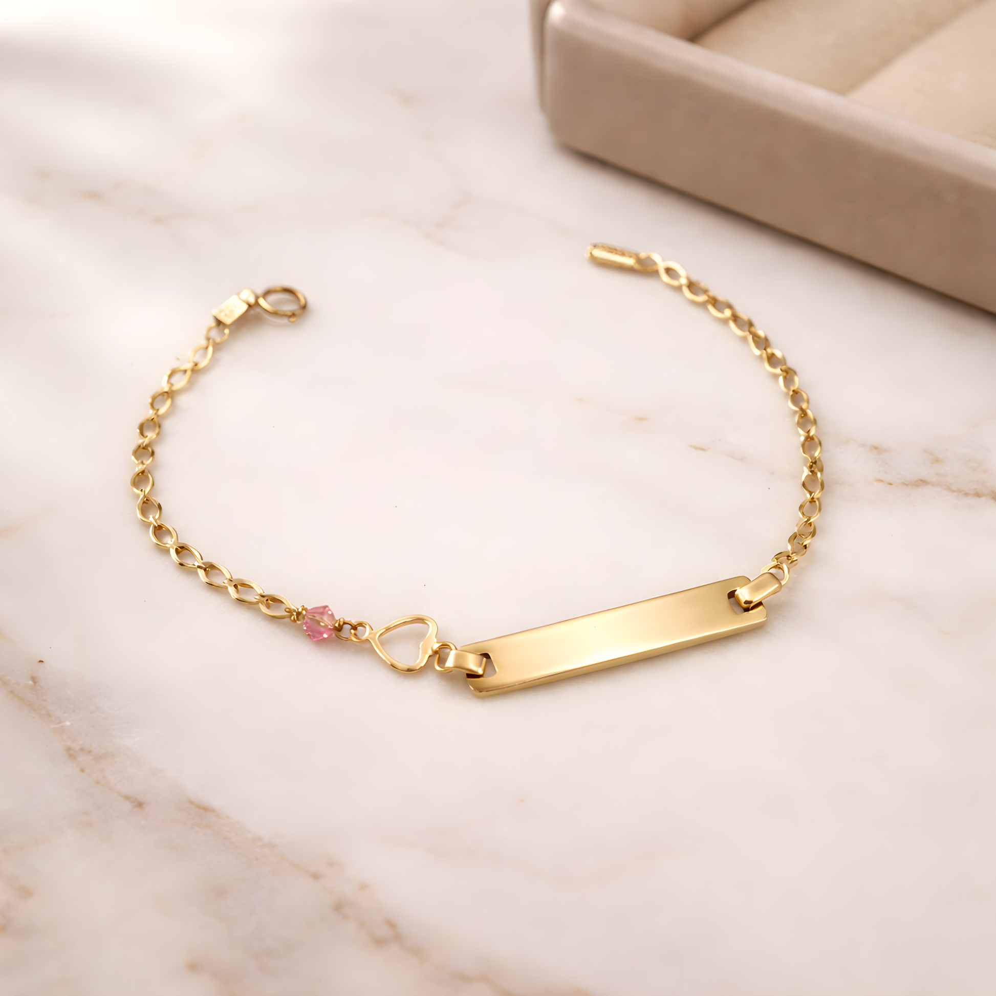 Gold bracelet with a heart charm on a satin surface