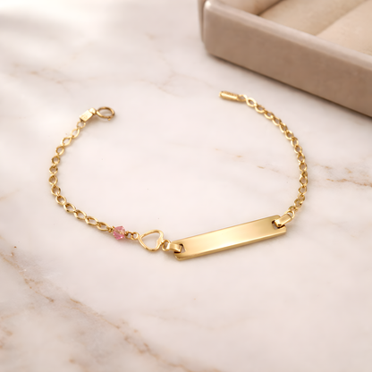 Gold bracelet with a heart charm on a satin surface