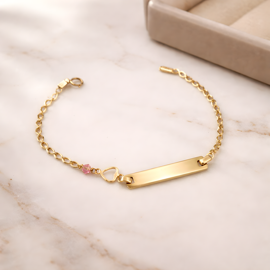 Gold bracelet with a heart charm on a satin surface