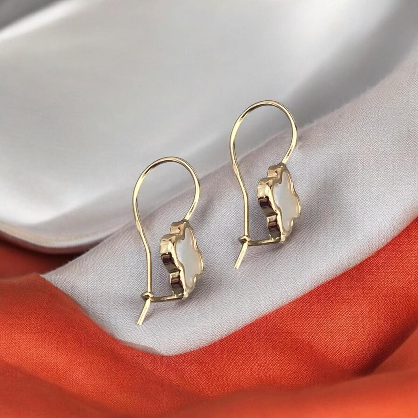 Elegant 14k yellow gold drop earrings featuring a delicate four-leaf clover motif inlaid with shimmering mother of pearl.
