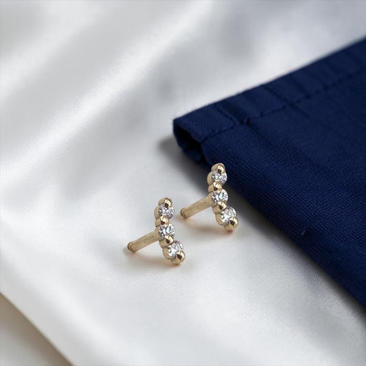 Elegant 14k yellow gold stud earrings featuring a delicate curved bar design accented with three sparkling lab-grown diamonds.