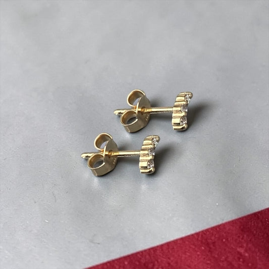 Elegant 14k yellow gold stud earrings featuring a delicate curved bar design accented with three sparkling lab-grown diamonds.