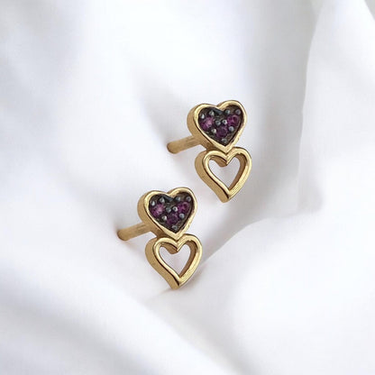 Elegant 14k yellow gold stud earrings featuring a double heart design, with one heart encrusted with small red stones.