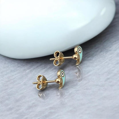 Delicate 14k yellow gold stud earrings featuring a protective evil eye motif accented with vibrant light blue enamel.