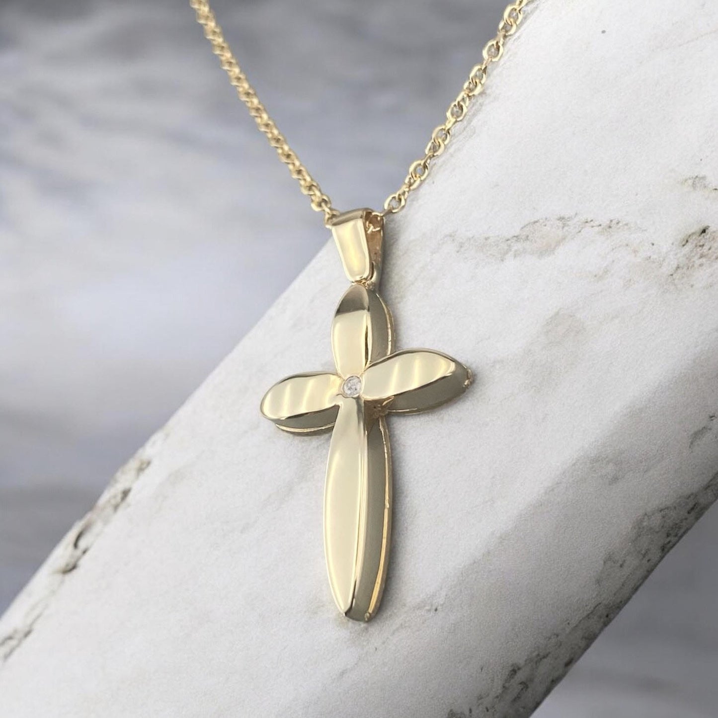 14k yellow gold cross pendant for women, featuring a unique floral-inspired petal design with a central sparkling zirconia stone.