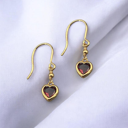 Elegant 14k yellow gold drop earrings featuring a delicate heart-shaped red garnet stone and a secure hook fastening.