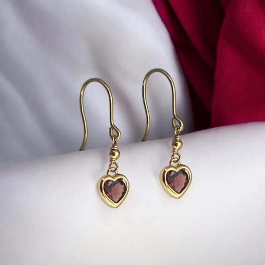 Elegant 14k yellow gold drop earrings featuring a delicate heart-shaped red garnet stone and a secure hook fastening.