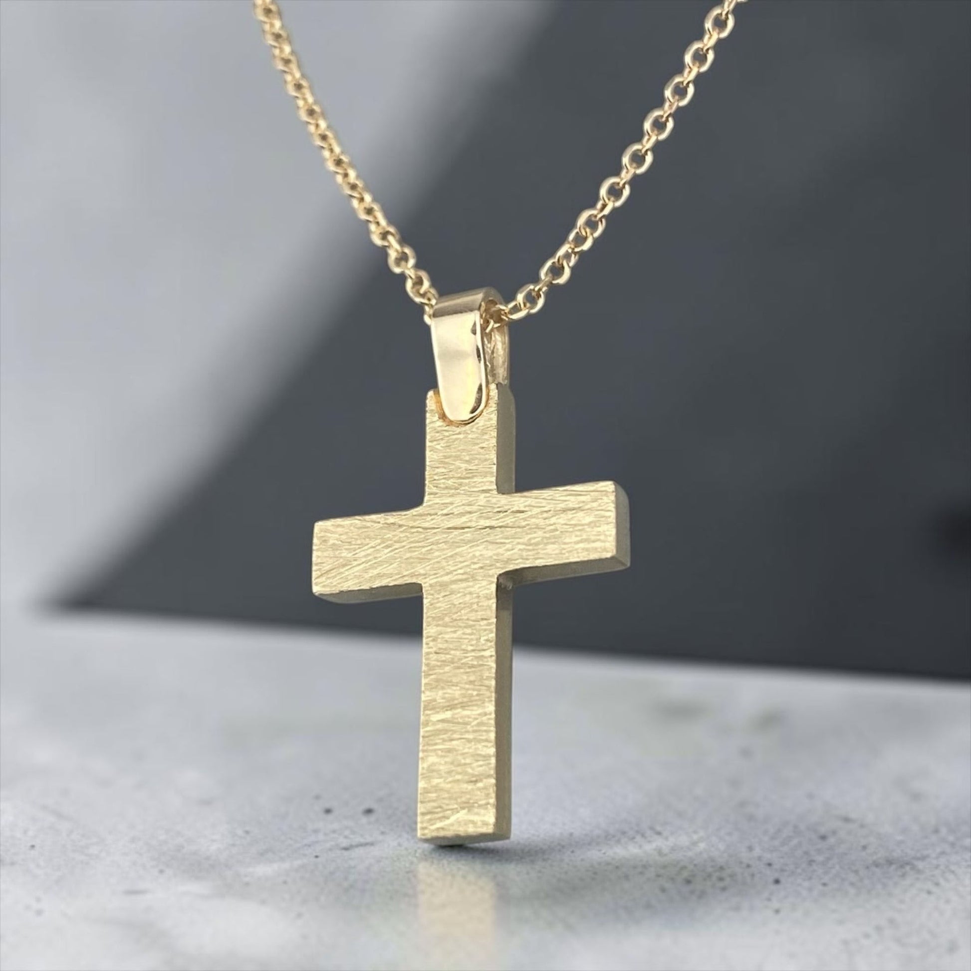 A 14K yellow gold men's cross pendant featuring a distinctive brushed matte finish design.