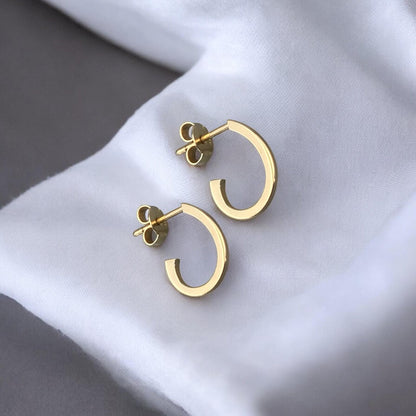Modern 14k yellow gold half hoop earrings with a minimalist open design.