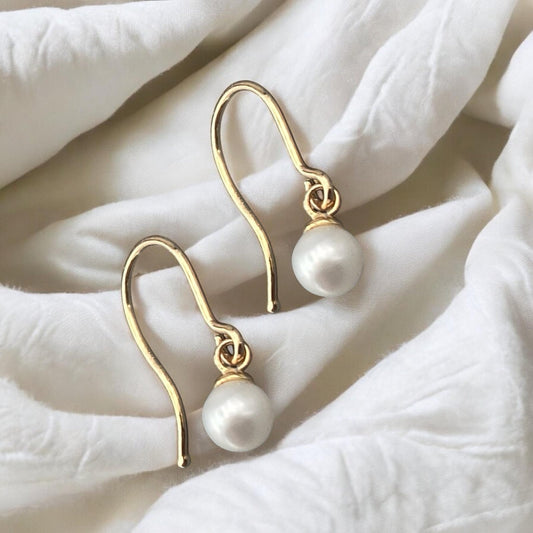 Elegant 14k yellow gold drop earrings featuring round white pearls and a minimalist polished hook design.