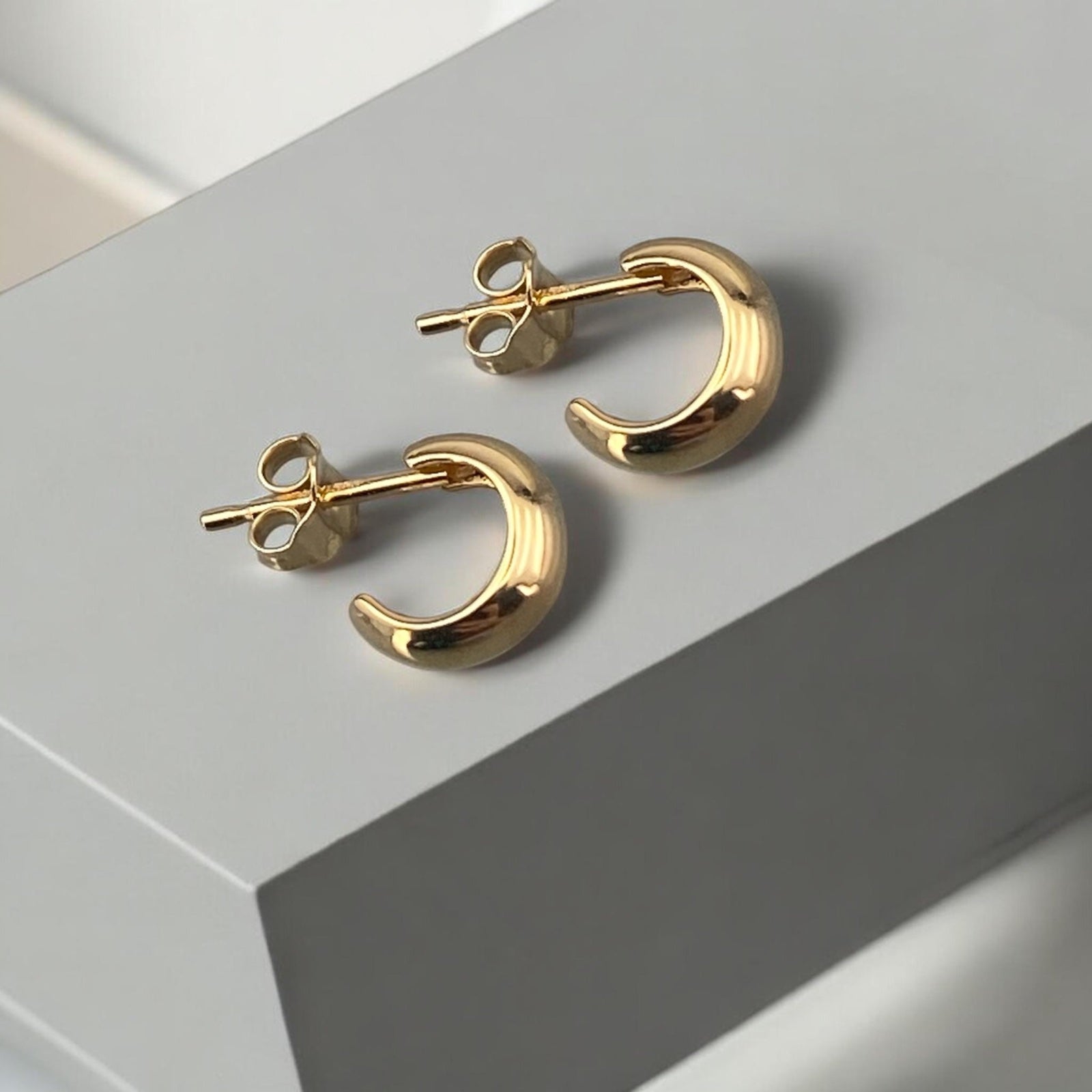 Minimalist 14k yellow gold small half-hoop stud earrings with a polished finish and secure post fastening.