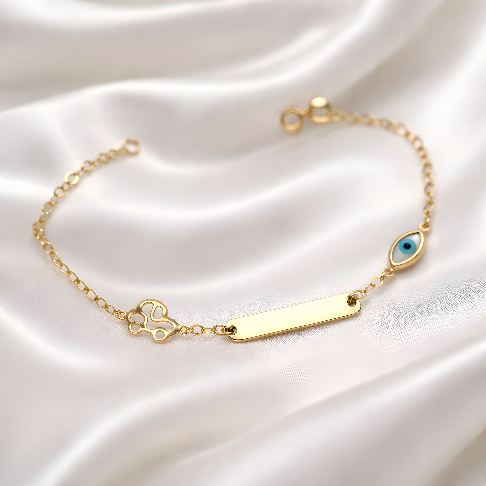 Gold bracelet with a blue eye charm and a gold car on a white satin background