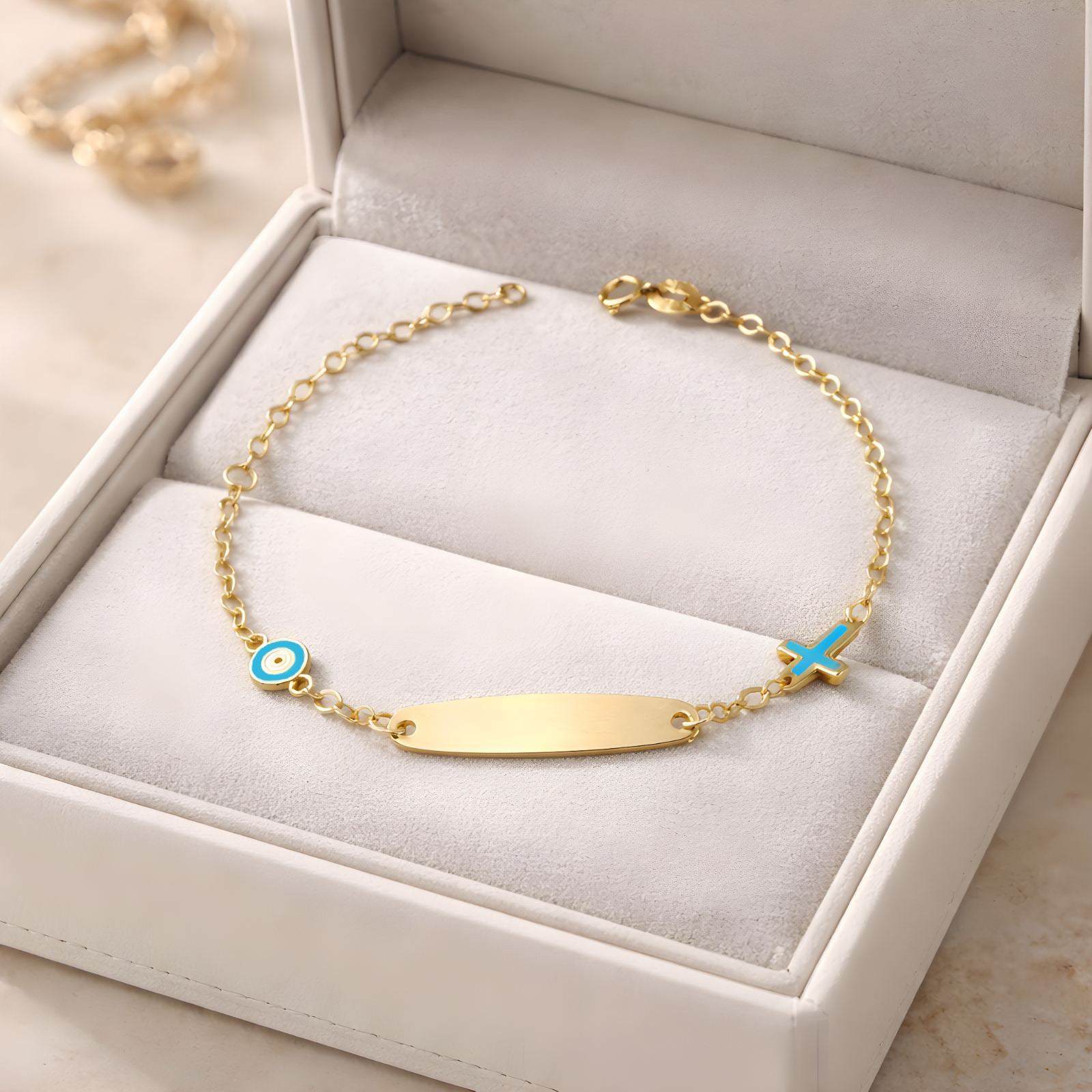 Children's 9k yellow gold ID bracelet featuring an blue eye charm and a cross charm, delicate baby jewelry.