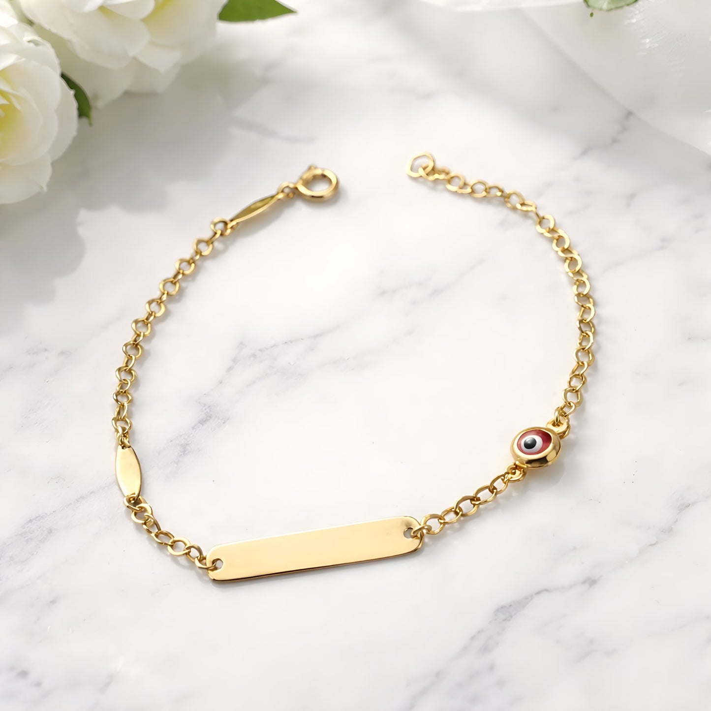Gold bracelet with a bar clasp and eye charm on a marble surface