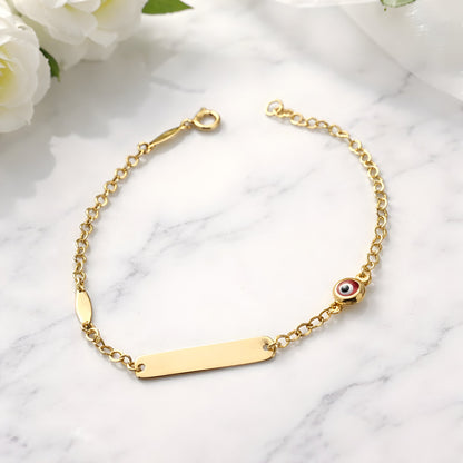 Gold bracelet with a bar clasp and eye charm on a marble surface
